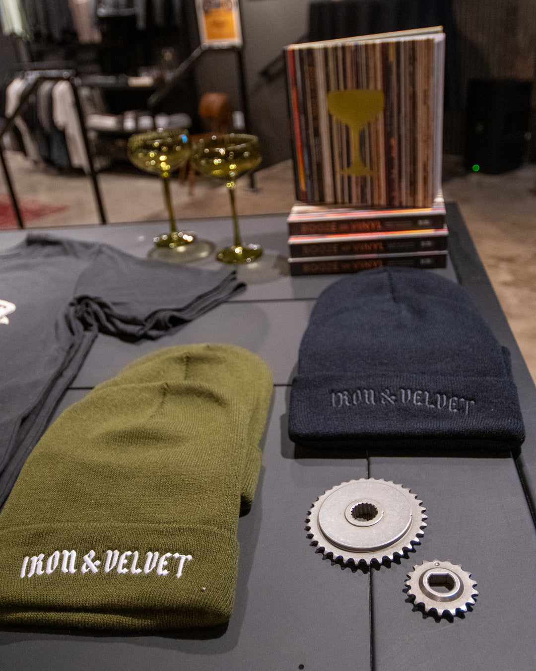 Green and black beanies with 'Iron & Velvet' branding on a gray surface with metal gears.
